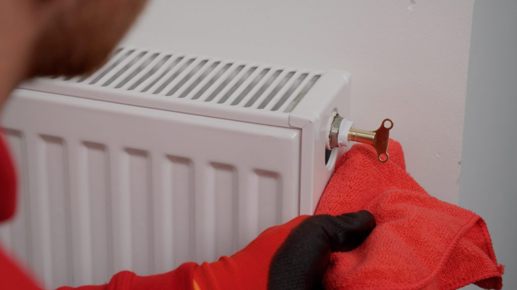 A person ready to bleed a radiator with the key inserted in the bleed valve