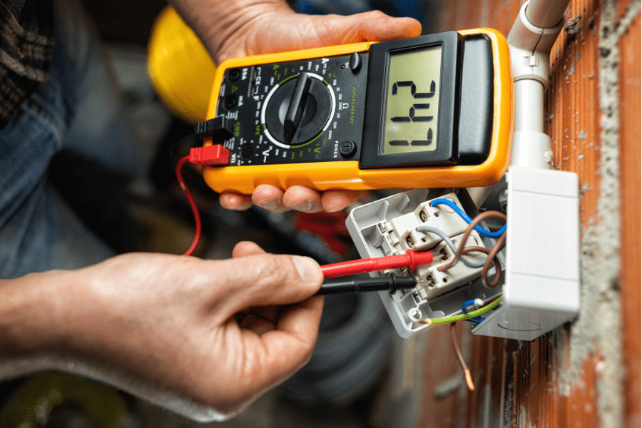 Electrician using voltage tester on an exposed light switch to ensure it is 'dead'.