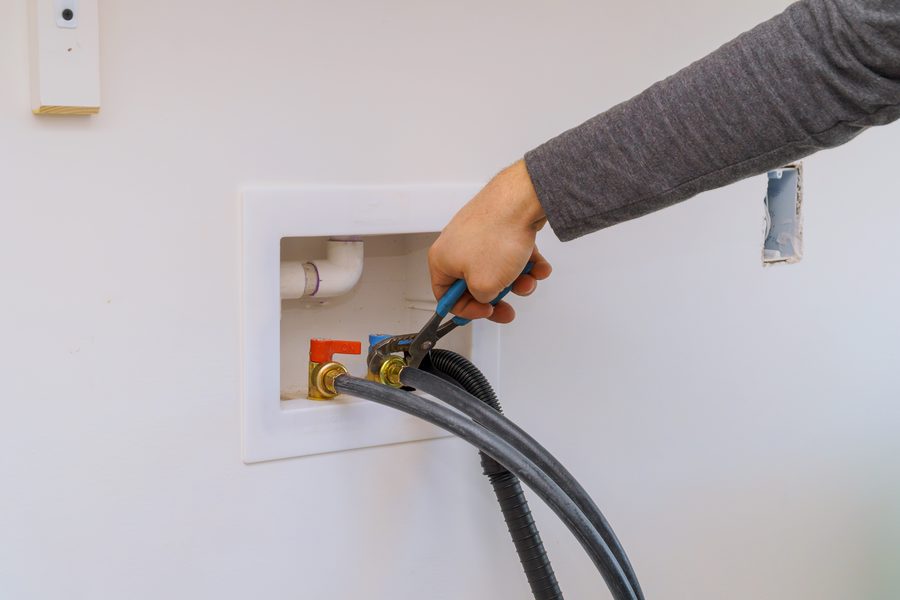 Hot and cold water valves being used to shut off mains water the appliance when disconnecting a washing machine.