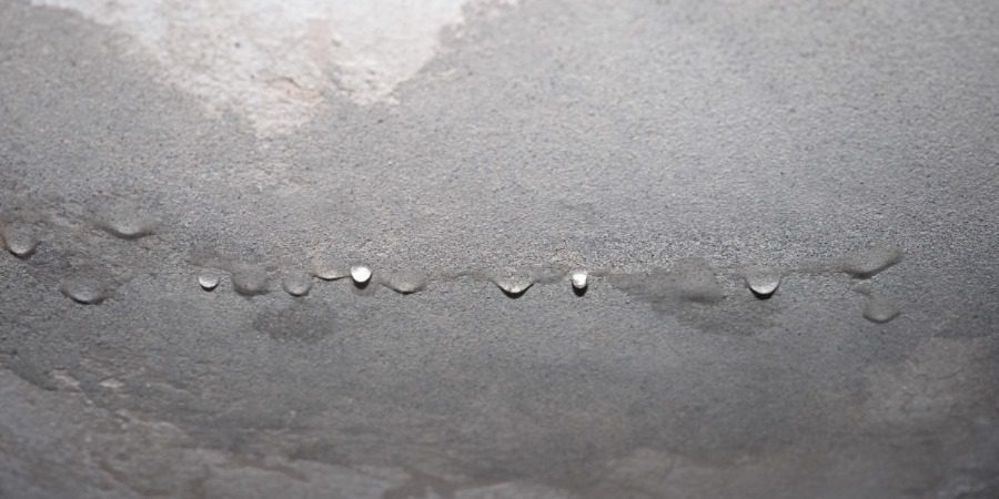 Water dripping through a white ceiling due to penetrating damp